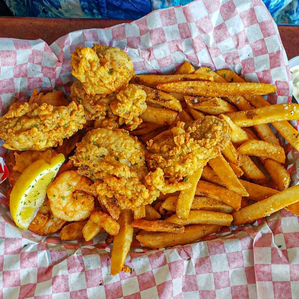 A basket of Graham's Landing fried seafood and french fries with a lemon wedge.