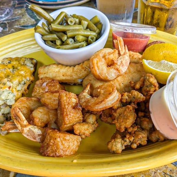 A yellow plate of fried shrimp, oysters, fish, green beans, and cheesy potatoes at Graham's Landing.