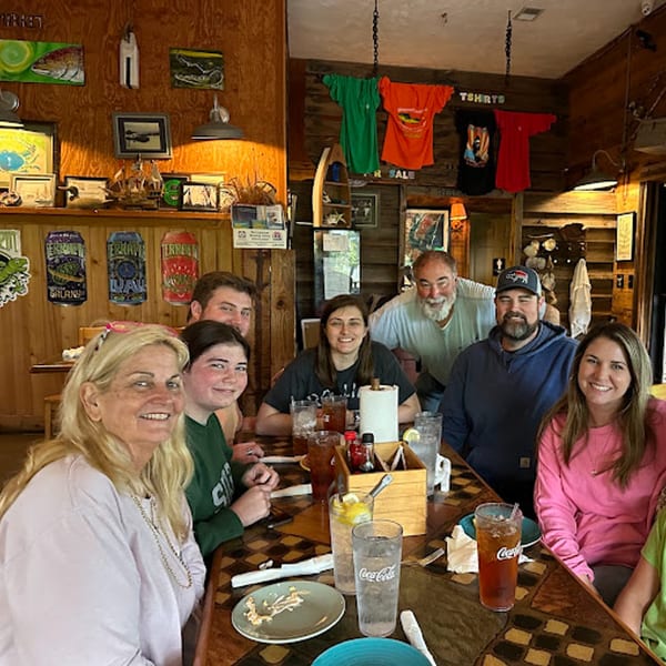 A family group smiles at a table in Graham's Landing, a seafood restaurant with rustic decor.