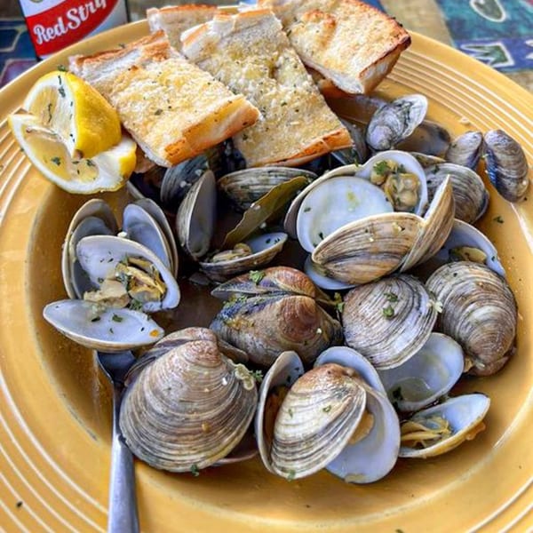 Steamed clams in a yellow bowl with garlic bread and lemon wedges, from Graham's Landing.