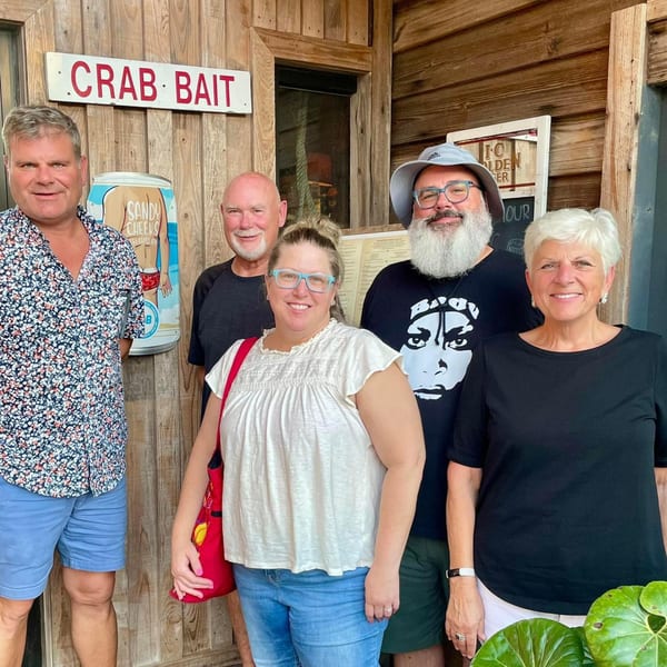 Five smiling people stand outside Graham's Landing, a rustic seafood restaurant with a "Crab Bait" sign.