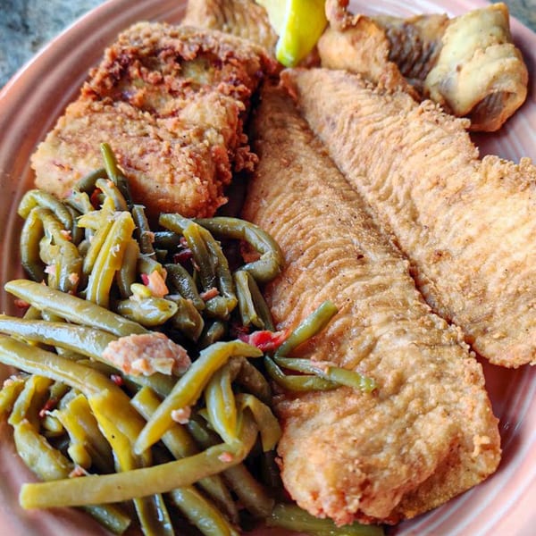 Fried fish fillets and green beans with bacon bits on a pink plate at Graham's Landing.
