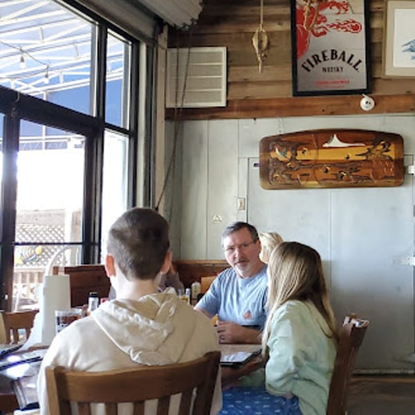 A family of three, including a man and two children, seated at a table inside Graham's Landing.